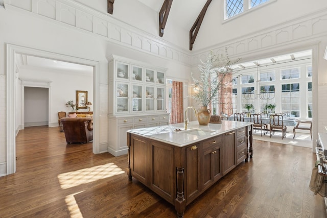 kitchen featuring high vaulted ceiling, dark wood-style flooring, a sink, and beamed ceiling