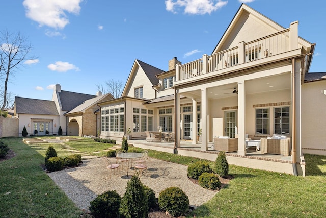 back of property featuring a ceiling fan, a balcony, a yard, a patio area, and an outdoor living space