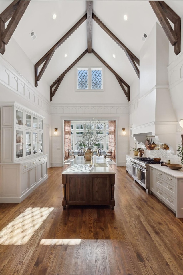 unfurnished living room with visible vents, high vaulted ceiling, dark wood finished floors, and beamed ceiling