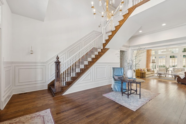 interior space with recessed lighting, a decorative wall, a high ceiling, wood finished floors, and an inviting chandelier