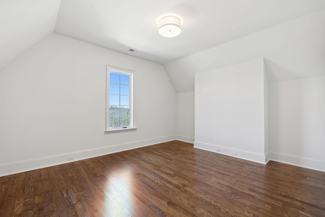 bonus room featuring visible vents, baseboards, vaulted ceiling, and dark wood finished floors