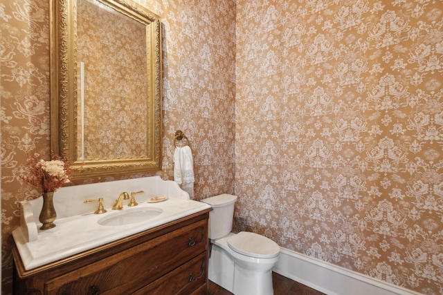 bathroom featuring vanity, toilet, and wallpapered walls