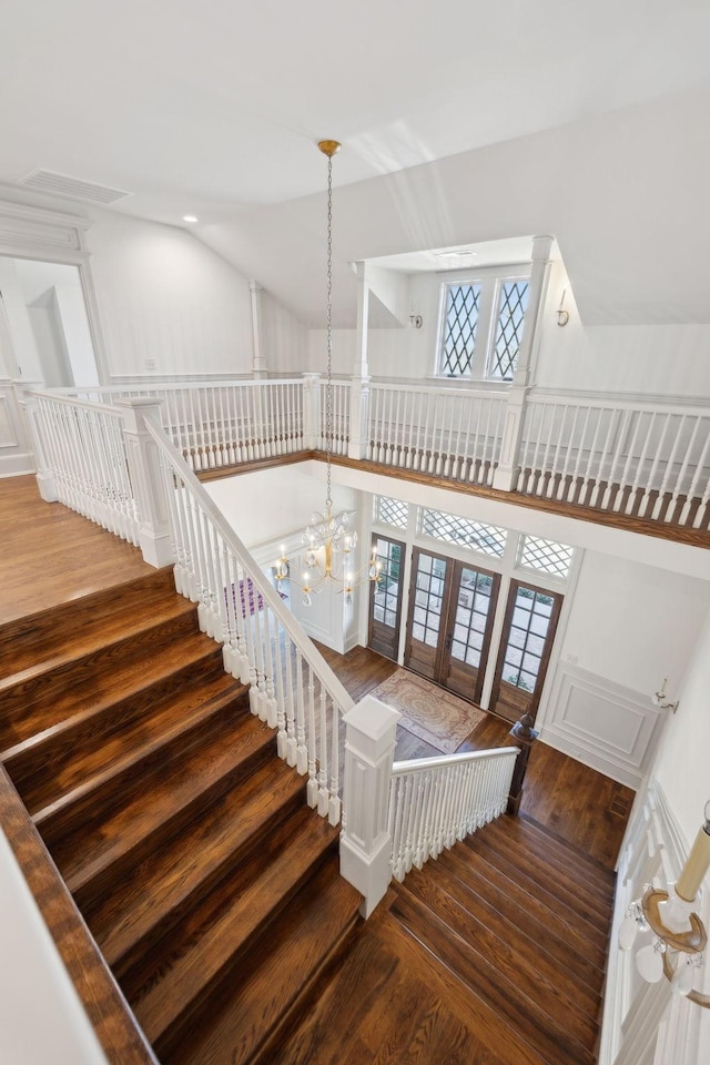 stairs featuring high vaulted ceiling, french doors, wood finished floors, and a notable chandelier