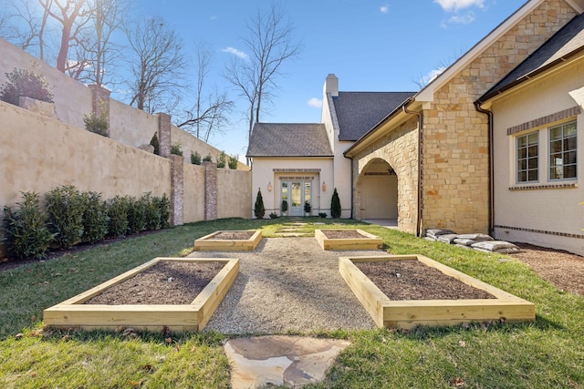 view of yard with fence, a vegetable garden, and french doors