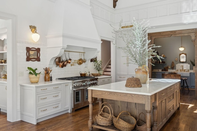 kitchen featuring range with two ovens, a center island, dark wood finished floors, light countertops, and decorative backsplash