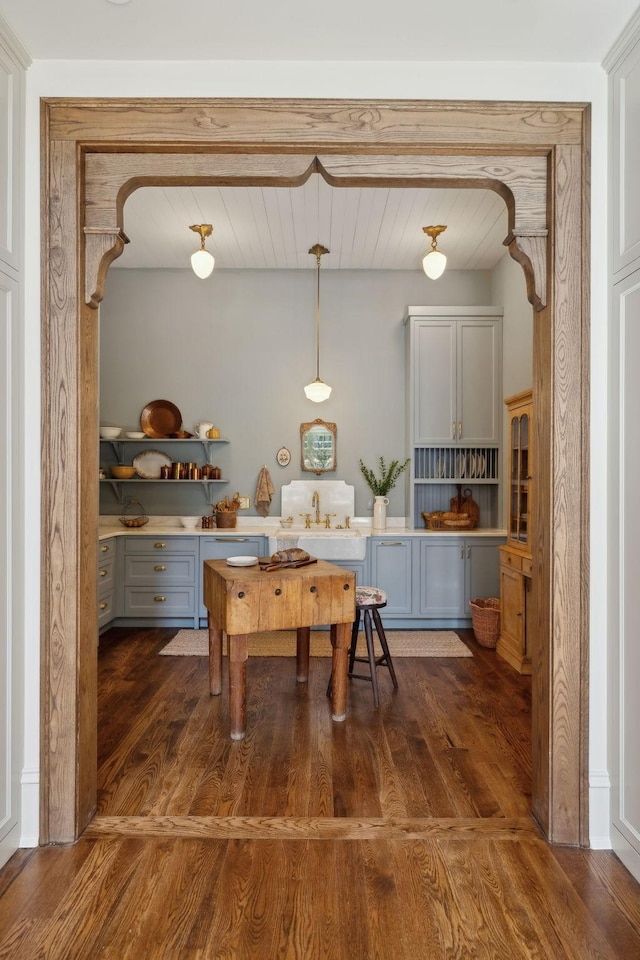 kitchen featuring arched walkways, pendant lighting, dark wood finished floors, open shelves, and gray cabinetry