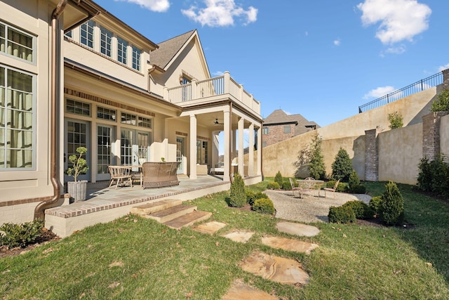 exterior space featuring a balcony, a patio area, fence, and a ceiling fan