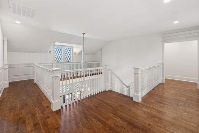 corridor with vaulted ceiling, wood finished floors, and visible vents