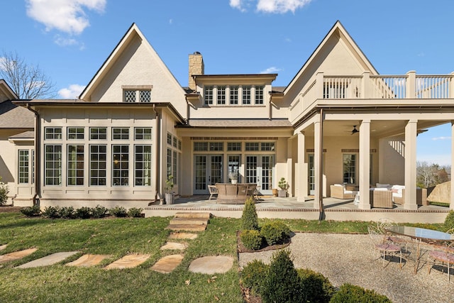 back of house with a balcony, an outdoor hangout area, french doors, a chimney, and a patio area