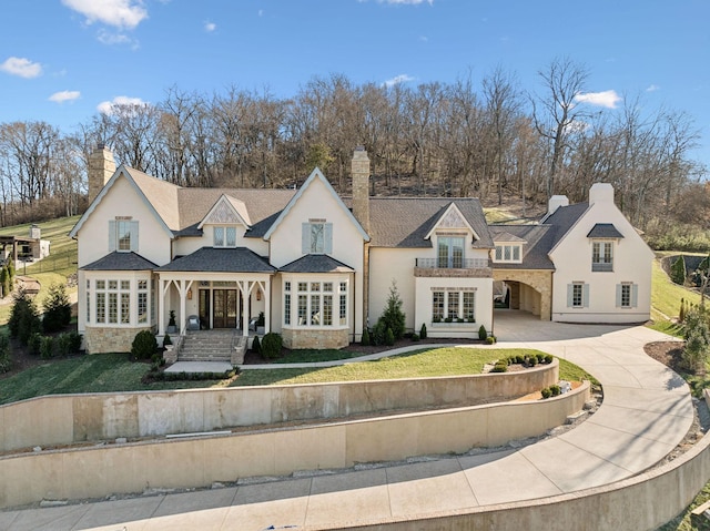 view of front facade with concrete driveway, stone siding, a front yard, and french doors