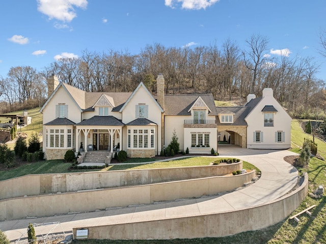 view of front facade with stone siding, concrete driveway, and a front yard