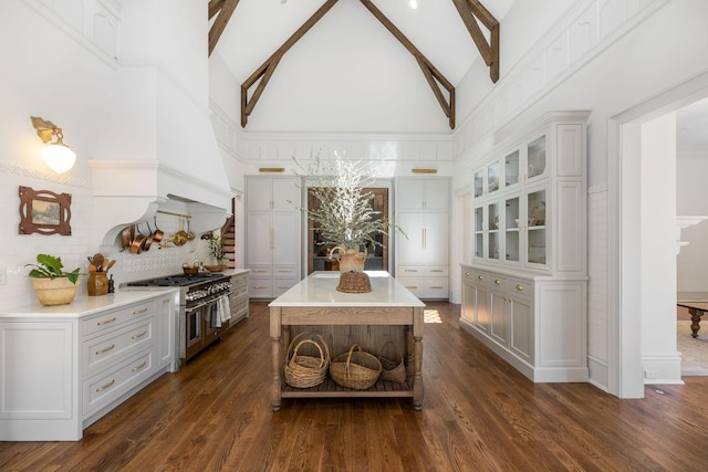 kitchen with range with two ovens, beam ceiling, light countertops, and dark wood-type flooring