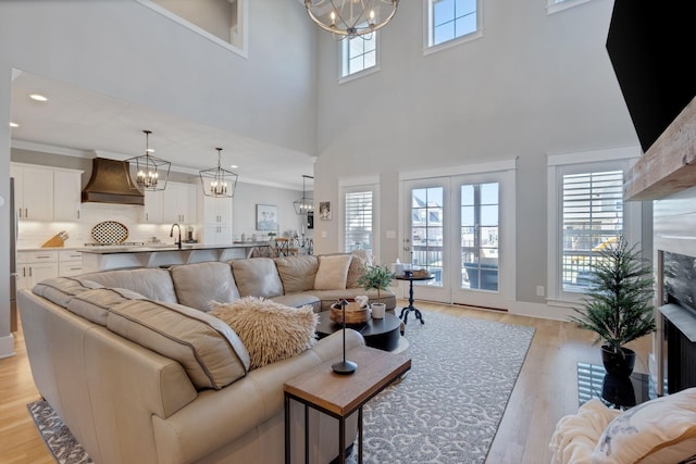 living room featuring crown molding, light wood-style flooring, and a notable chandelier