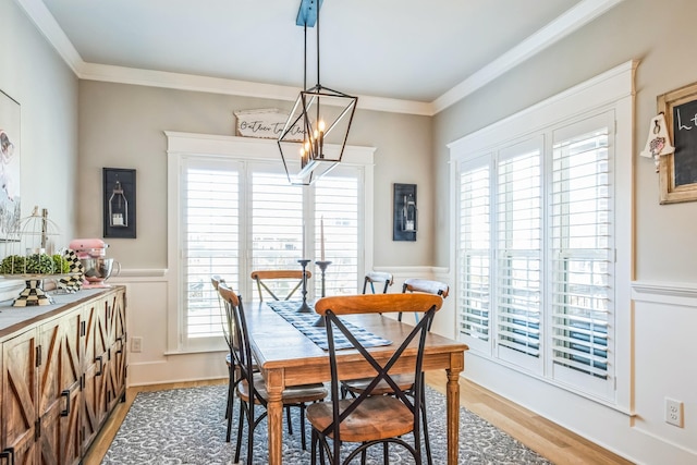 dining room with ornamental molding, light wood-type flooring, and a wainscoted wall