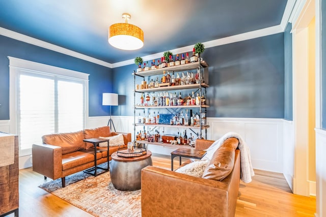 sitting room featuring ornamental molding, wainscoting, and wood finished floors