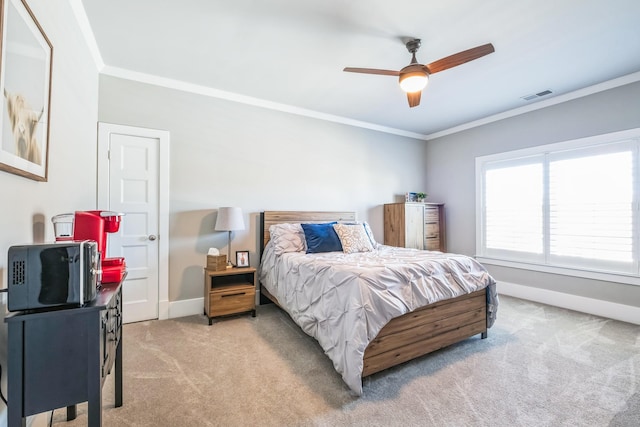 carpeted bedroom featuring ceiling fan, ornamental molding, visible vents, and baseboards