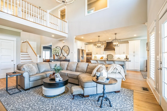 living room with visible vents, light wood-style flooring, stairway, a chandelier, and recessed lighting