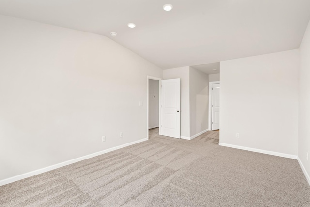 unfurnished room with recessed lighting, baseboards, vaulted ceiling, and light colored carpet