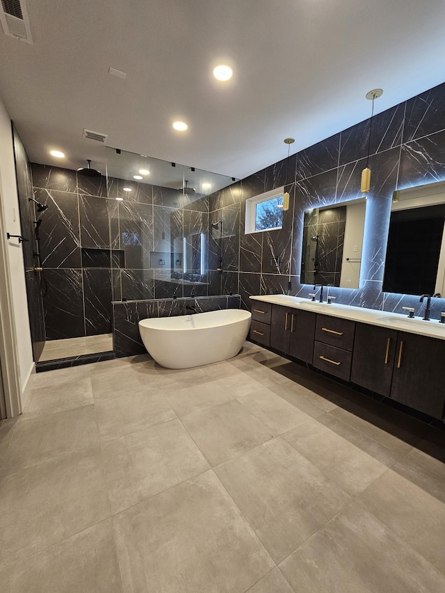 bathroom featuring double vanity, visible vents, a soaking tub, walk in shower, and tile walls