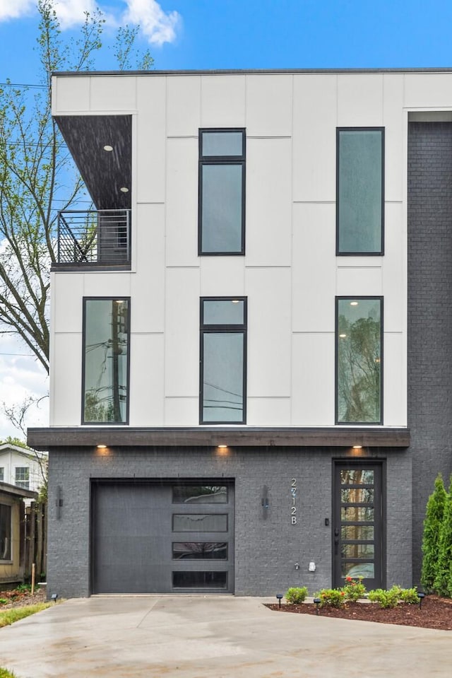 contemporary house with driveway, an attached garage, and brick siding