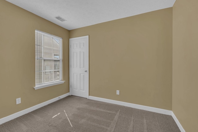 carpeted spare room with visible vents, a textured ceiling, and baseboards