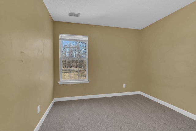 spare room with carpet, a textured ceiling, visible vents, and baseboards