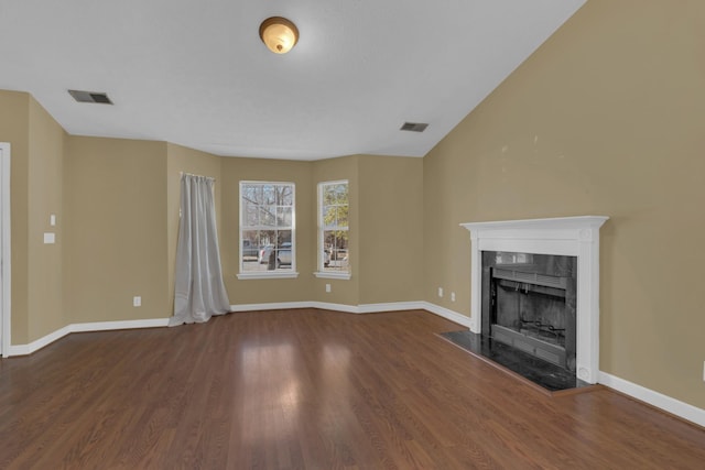 unfurnished living room featuring baseboards, visible vents, wood finished floors, and a high end fireplace