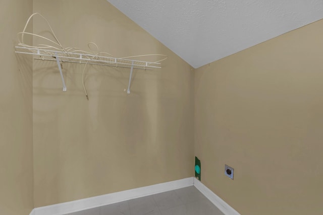 clothes washing area with laundry area, electric dryer hookup, baseboards, and a textured ceiling