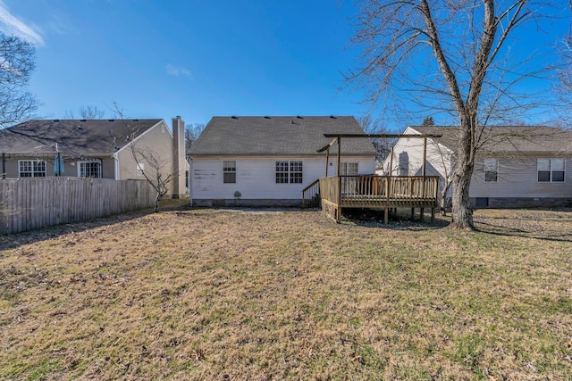 rear view of property with a yard, a deck, and fence