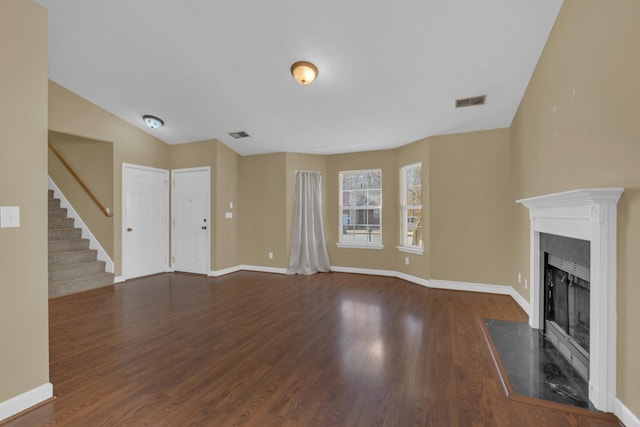 unfurnished living room with stairs, wood finished floors, a fireplace with flush hearth, and baseboards