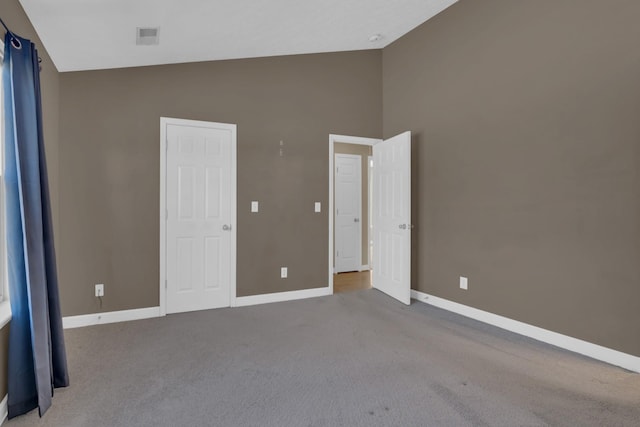 unfurnished bedroom with carpet floors, high vaulted ceiling, visible vents, and baseboards