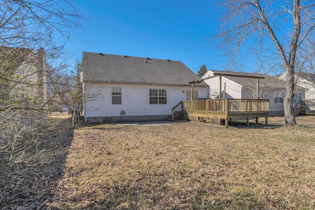 back of property featuring roof with shingles, a yard, and a deck