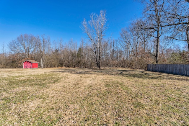 view of yard featuring a storage unit, fence, a garage, driveway, and an outdoor structure