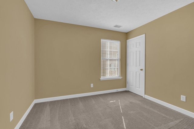 carpeted empty room featuring visible vents, a textured ceiling, and baseboards