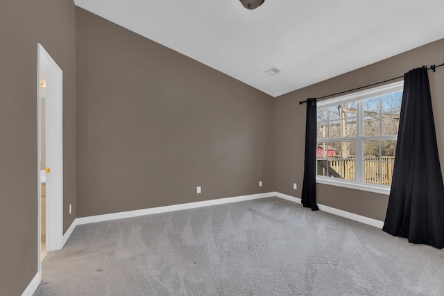 empty room with lofted ceiling, carpet, visible vents, and baseboards