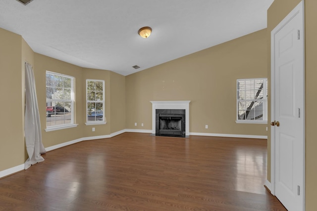 unfurnished living room with a fireplace, baseboards, vaulted ceiling, and dark wood-type flooring