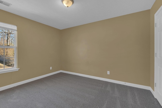 spare room with baseboards, visible vents, dark colored carpet, and a textured ceiling