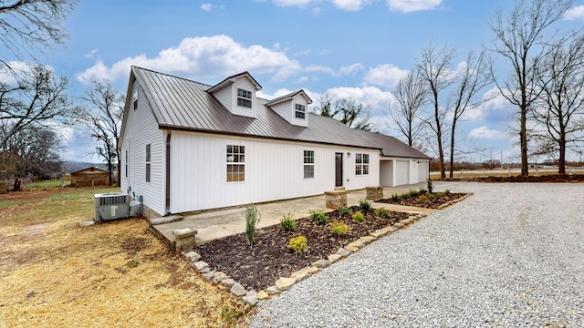 view of front of house with metal roof, driveway, central AC, and a garage