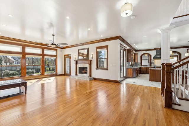 living room with light wood-type flooring, ornate columns, plenty of natural light, and a premium fireplace