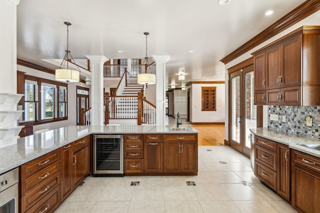 kitchen featuring light tile patterned floors, decorative backsplash, wine cooler, crown molding, and a sink