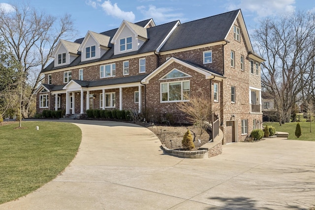 view of front facade featuring concrete driveway, brick siding, and a front lawn