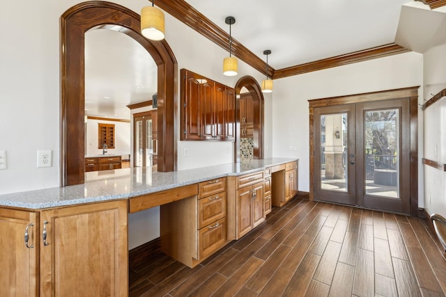 kitchen with hanging light fixtures, light stone countertops, wood tiled floor, crown molding, and french doors