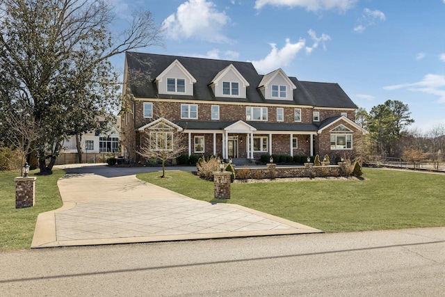 view of front of home with a porch, a front lawn, concrete driveway, and brick siding