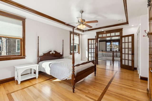 bedroom featuring light wood-type flooring, baseboards, ornamental molding, and a raised ceiling