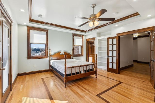 bedroom with ornamental molding, a raised ceiling, and french doors