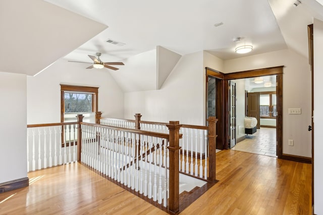 hallway featuring an upstairs landing, wood finished floors, visible vents, and a healthy amount of sunlight