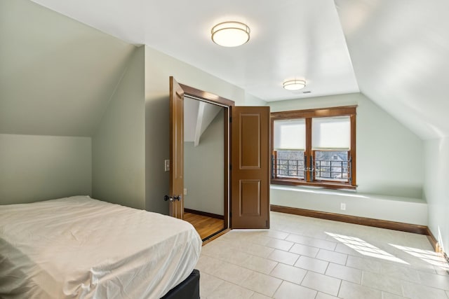 bedroom with lofted ceiling, visible vents, and baseboards