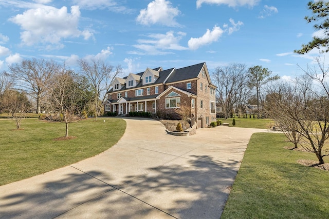 view of front facade with driveway, brick siding, and a front yard