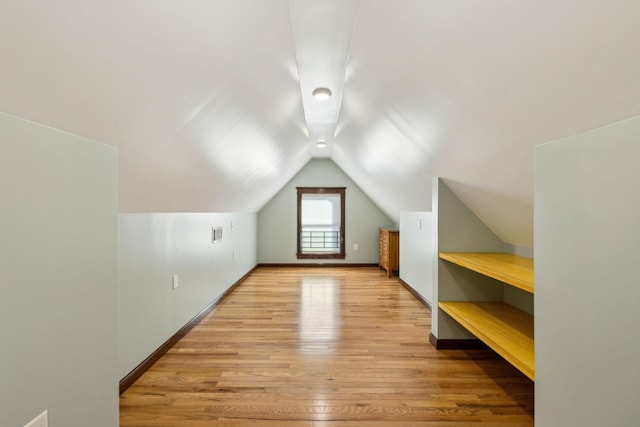 additional living space featuring light wood-style flooring, visible vents, baseboards, and vaulted ceiling