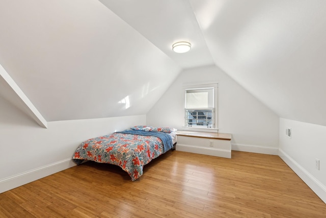 bedroom with lofted ceiling, light wood-style floors, and baseboards